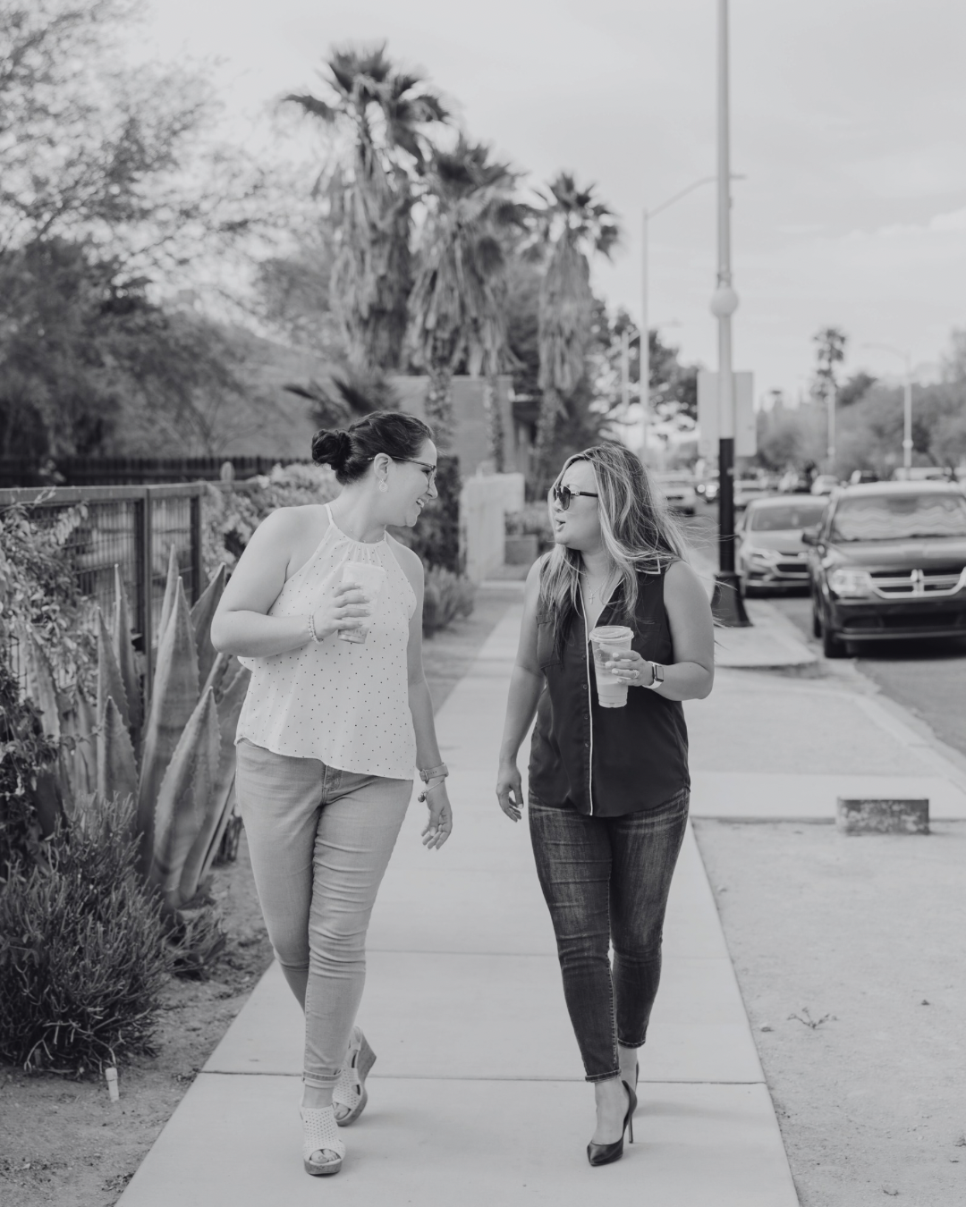 Two women talking while walking with a cup in hand